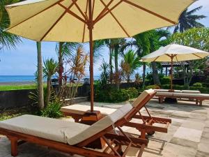 a couple of chairs and umbrellas on a patio at Melaya beach resort 3 in Penginuman