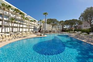 a large swimming pool with chairs and a building at Iberostar Waves Cristina in Playa de Palma