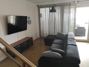 ein Wohnzimmer mit einem schwarzen Sofa und einem Flachbild-TV in der Unterkunft La Casa del Mirlo Azul - Peñíscola in Peñíscola