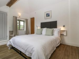a bedroom with a large bed with white sheets at The Coach House in Ludlow