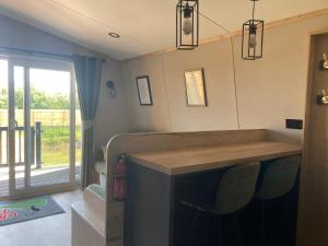 a room with a bar with chairs and a window at Chapel Fields Holiday Park in Chapel Saint Leonards