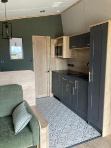 a kitchen with blue cabinets and a green wall at Chapel Fields Holiday Park in Chapel Saint Leonards