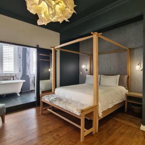 a bedroom with a canopy bed and a bath tub at What’s behind the green door! in Cape Town