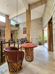 Habitación con mesa, 2 sillas y pared de ladrillo. en Finca Agua Salada, en Xochitepec