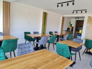 a dining room with wooden tables and green chairs at Pensiunea Lotus Corbu in Corbu