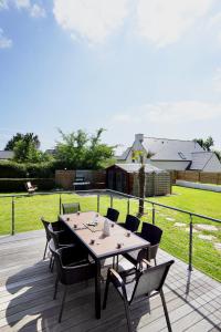 Una terraza de madera con una mesa y sillas. en Villa Anne - 500m de la mer - SPA, en Moëlan-sur-Mer