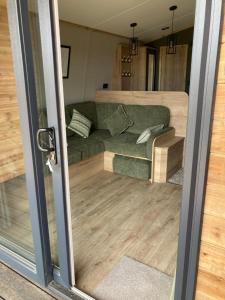 a living room with a green couch in a trailer at Chapel Fields Holiday Park in Chapel Saint Leonards