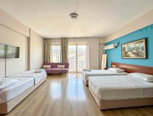 a hotel room with three beds and a tv at Kekik Butik Otel in Çeşme