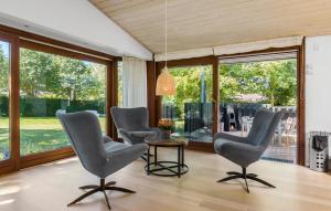 a living room with chairs and a table and large windows at Awesome Home In Græsted With Sauna in Græsted