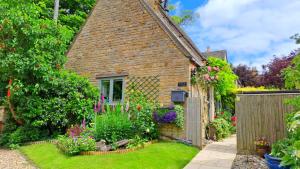 an old brick house with a garden in front of it at Graziers Cottage - character Cotswold cottage with inglenook, parking and pub nearby in Cheltenham