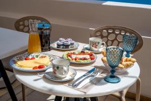 a white table with plates of food and cups and drinks at Passion Blue Villas in Oia