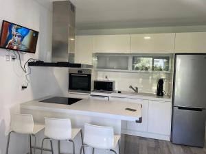 una cocina con armarios blancos y una encimera con sillas blancas en Blue Fish, en Pefkohori