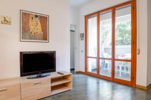a living room with a flat screen tv on a wooden cabinet at Appartamento con piscina a 100metri dal mare in Castiglioncello