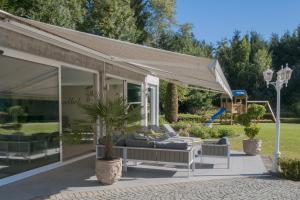 a patio with awning and chairs and a playground at Luxurious Villa 't Kasteelhof in Veulen