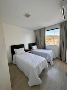 a hotel room with two beds and a large window at Gontijo Apart Hotel in Itajubá