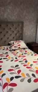 a bedroom with a bed with a flowered comforter at Residence amwej sousse in Sousse