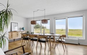 une salle à manger avec une table, des chaises et des fenêtres dans l'établissement 4 Bedroom Beach Front Home In Thyholm, à Thyholm