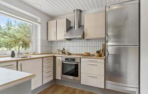 une cuisine avec des armoires blanches et un réfrigérateur en acier inoxydable dans l'établissement 4 Bedroom Beach Front Home In Thyholm, à Thyholm