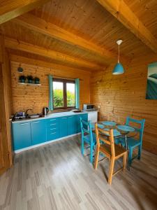a kitchen with blue cabinets and a table and chairs at Tęczowe Domki in Władysławowo