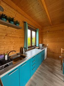 a kitchen with blue cabinets in a wooden cabin at Tęczowe Domki in Władysławowo