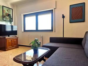 a living room with a couch and a table and a tv at Mountain View Beach House in Costa da Caparica