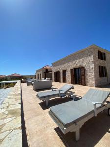 a patio with chaise lounges and tables on a building at Villa Aristoteles in Halki