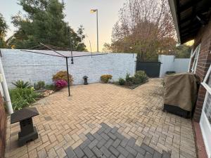 eine gemauerte Terrasse mit einem Sonnenschirm in einem Hinterhof in der Unterkunft Cottage - Sleeps 4 - Pet friendly - Pool - Parking in Johannesburg
