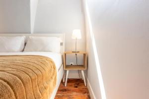 a bed with a side table with a lamp on it at GuestReady - Sunshine Belém in Lisbon