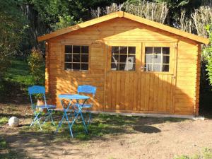 une petite cabane en bois avec deux chaises et une table dans l'établissement Fleur De Soleil, à Saint-Jouin-Bruneval