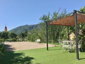 a table and chairs under an umbrella on a lawn at La Maison Vésubie in Roquebillière