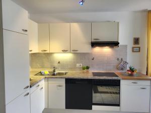 a kitchen with white cabinets and a sink at Apartment Lakeview La Marea by Interhome in Piazzogna