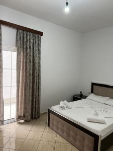 a bedroom with a bed with white sheets and a window at Villa AlMar in Sarandë