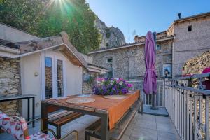 a table with a purple umbrella and flowers on a balcony at Maison Bossanne in Barbières