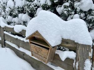 a wooden bird house covered in snow on a fence at Chalet Alwin by Interhome in Heidersbach