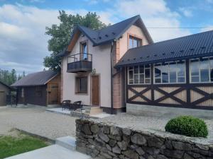 a house with a black roof and a stone wall at Кукул in Vorokhta