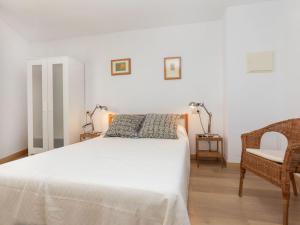 a bedroom with a white bed and a chair at Apartment Marinada by Interhome in Tossa de Mar