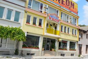 a yellow building with a neon sign on it at Neon Guest Rooms in Shumen
