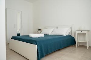 a white bedroom with a bed with a blue blanket at A CASA DI CRISTINA in Lampedusa