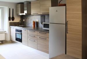 a kitchen with a white refrigerator and wooden cabinets at La Maison de Berthe - Havre de paix dans la campagne - Entièrement rénovée et équipéé in Montmaur +21 photos
