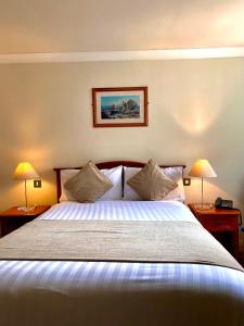 a bedroom with a large bed with two lamps at An Cruiscin Lan in Spiddal