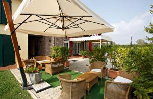 une terrasse avec des chaises, des tables et un parasol dans l'établissement Hotel Gabarda, à Carpi