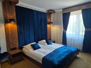 a bedroom with a bed with a blue wall at Dworek Nad Stawem & Łaźnia Piwna in Ostrów Mazowiecka