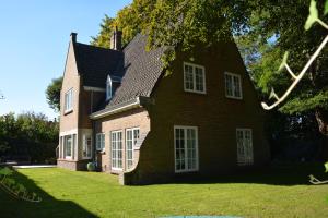Casa grande de ladrillo marrón con ventanas blancas en Le Coin Vert, en Brujas