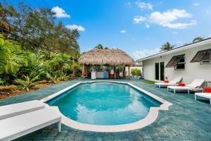 a swimming pool with chairs and a house at Eccentric home with pool tiki hut & outdoor kitchen in Pompano Beach