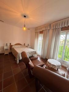 a bedroom with a bed and a couch and windows at Los Ogíjares in Ogíjares