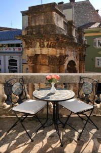 a table and chairs with a vase of flowers on a balcony at Boutique Suites Joyce in Pula