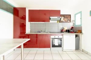 a kitchen with red cabinets and a white refrigerator at les berges de l'Oust in Malestroit