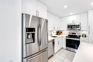 a kitchen with white cabinets and a stainless steel refrigerator at Bungalow with large backyard 5 min from beach in Pompano Beach