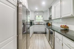 Una cocina con gabinetes blancos y un refrigerador de acero inoxidable. en Charlotte Home with Yard - Near Spectrum Center!, en Charlotte