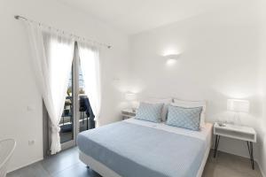 a white bedroom with a bed and a window at Alexander Suites in Drios